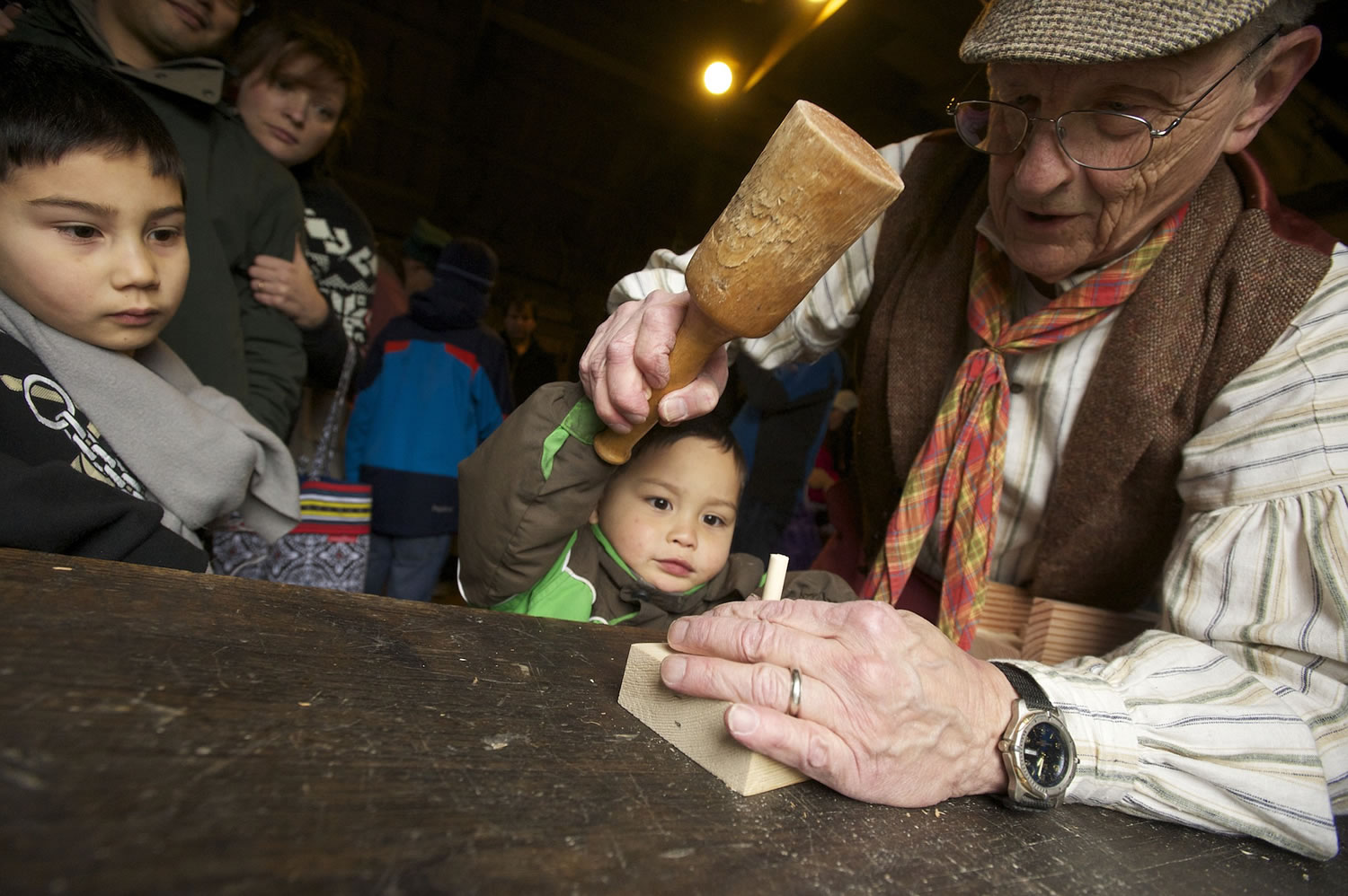 Micah Chong, 3, gets help building a toy top from volunteer Dick Pettigrew at Fort Vancouver during the annual Christmas at the Fort event.