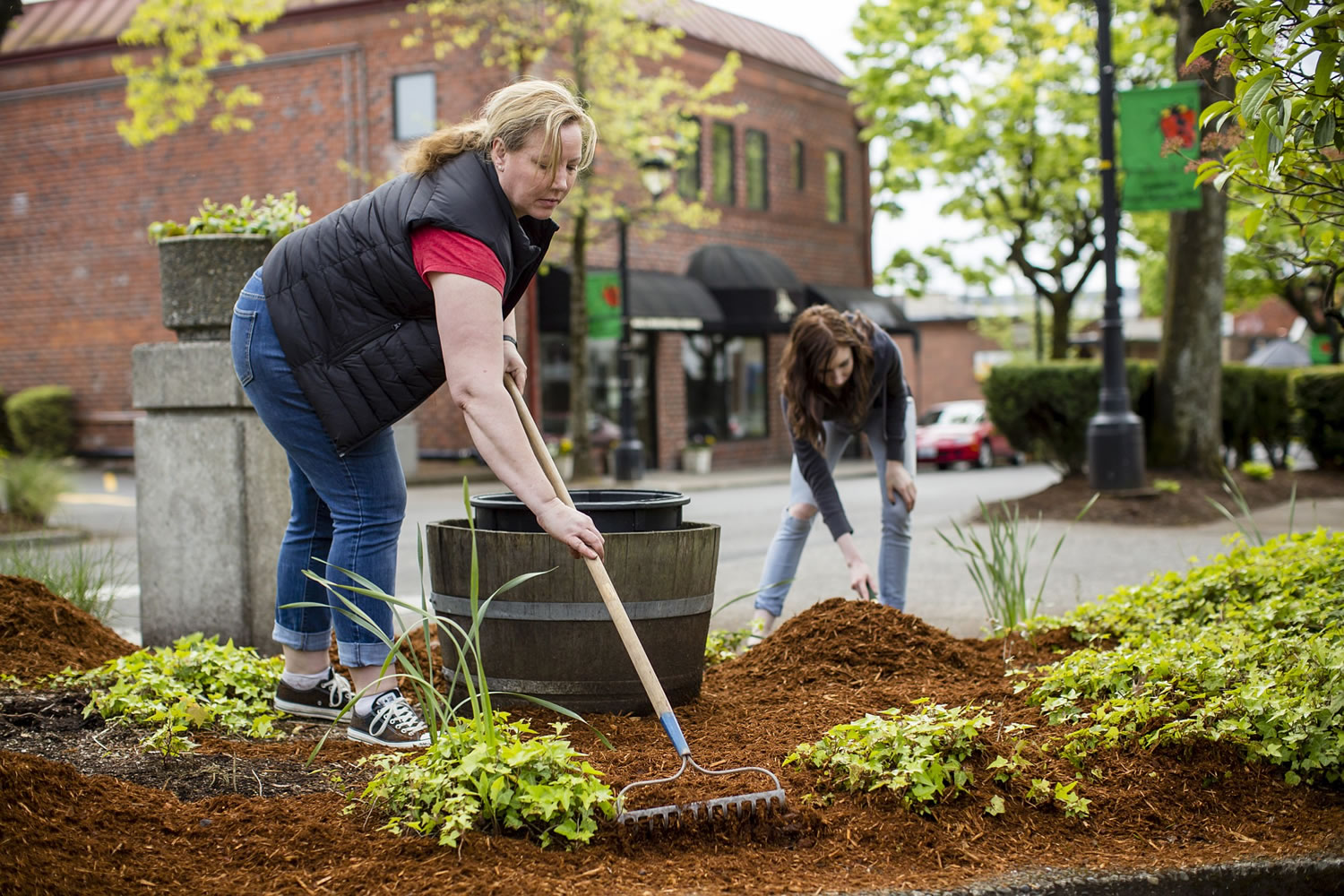 Camas City Councilwoman Shannon Turk helps spread bark dust along Northeast Fourth Avenue with other volunteers in downtown Camas on Sunday afternoon.