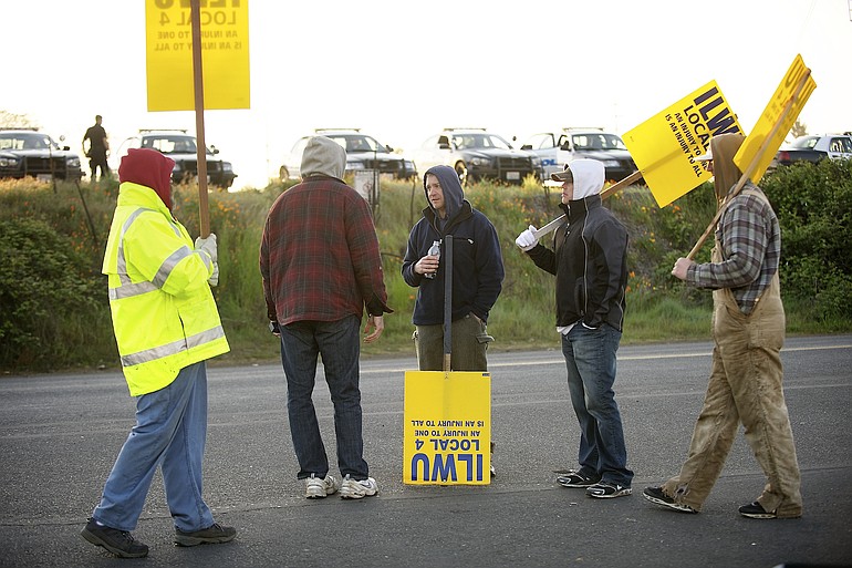 Vancouver police watch over ILWU Local 4 supporters holding signs outside the main gate to United Grain early Wednesday morning in Vancouver.