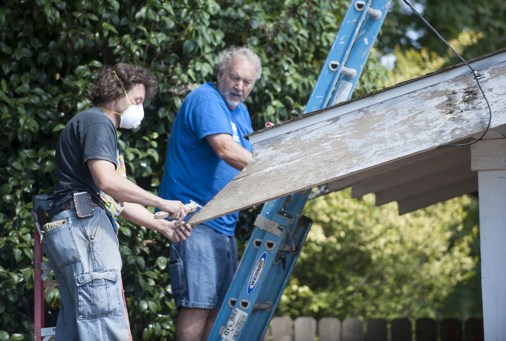 Habitat for Humanity volunteers John Furniss, left, and Denny Ellor work Wednesday on the roof of Joyce Evans Hall.