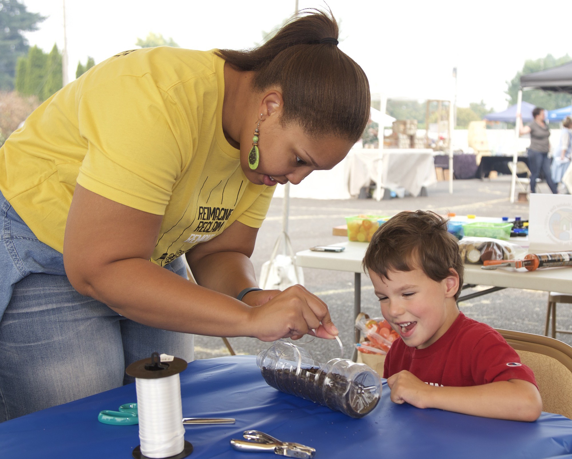 Volunteer Jessica Clay helps Patrick Gallegos, 6, of Vancouver plant sunflower seeds in a plastic-bottle planter at the Evergreen Habitat for Humanity first Remaker's Fair to benefit the Women Build program.