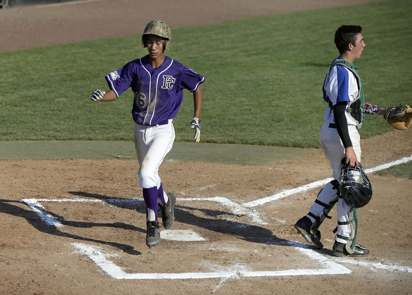 Pearl City's Rayson Carriaga, left, strides past Manhattan Beach catcher Jake Gordon to score in the first inning Wednesday evening, August 12, 2015 at Propstra Stadium.