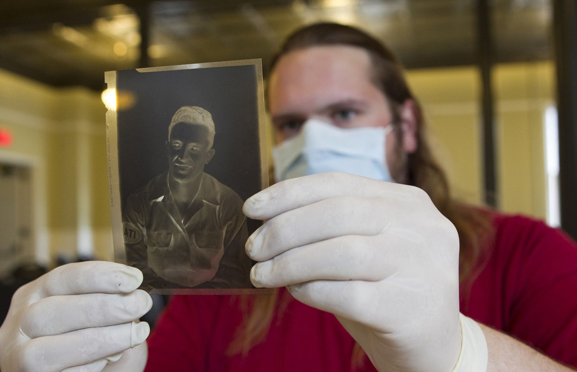 Chris Heagy examines the negative of a photo of Giovanni D. Donato taken in 1943. It is one of thousands of photos taken of soldiers, civilian workers and Italian prisoners, such as Donato, who were at Vancouver Barracks during World War II.