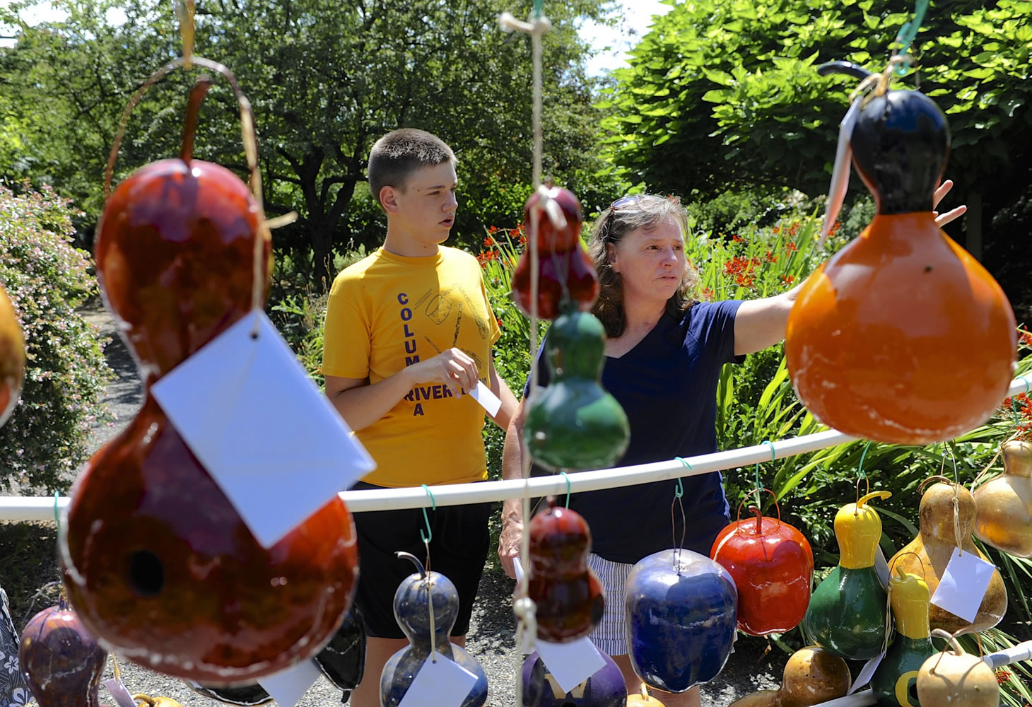 Mona Fuerstenau, right, and Ben Fisher make a selection from Dick Mills' gourd birdhouses at Art in the Garden in Brush Prairie on Sunday.