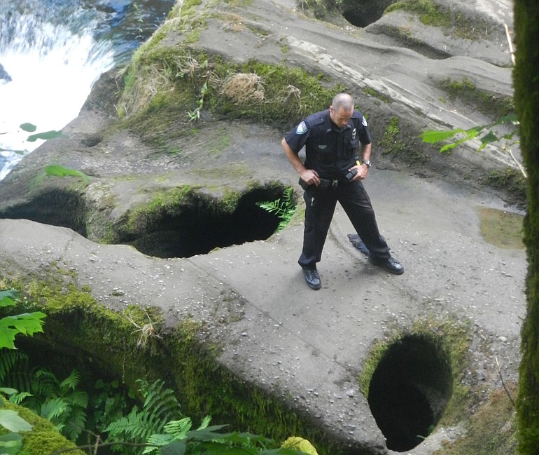 A police officer surveys an area known as the Potholes where an 11-year-old Vancouver boy drowned Tuesday afternoon in Camas.