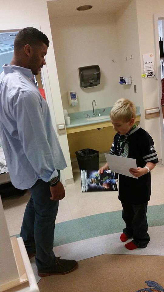 Photo provided by Kelly Conover
Jack Conover, 7, takes a look at the Seattle Seahawks yearbook and autographed photo quarterback Russell Wilson gave him Tuesday.