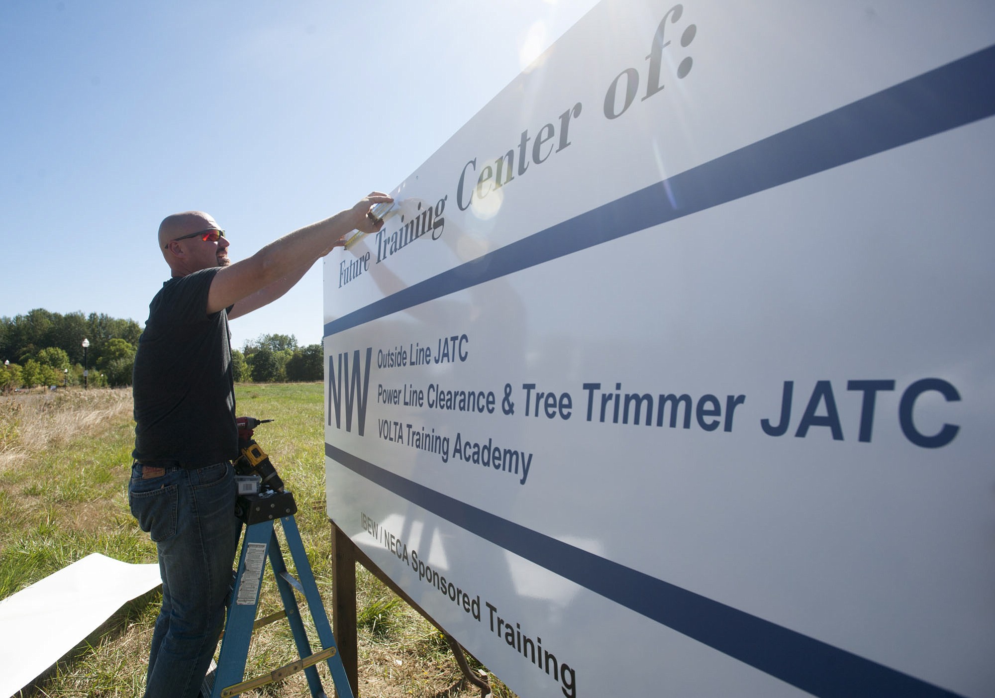 Mike Kiessling, director of the Northwest Line Construction Industry's Joint Apprenticeship Training Committee, installs a sign on the training program's new property at 1705 S.E. 17th St. in  Battle Ground.