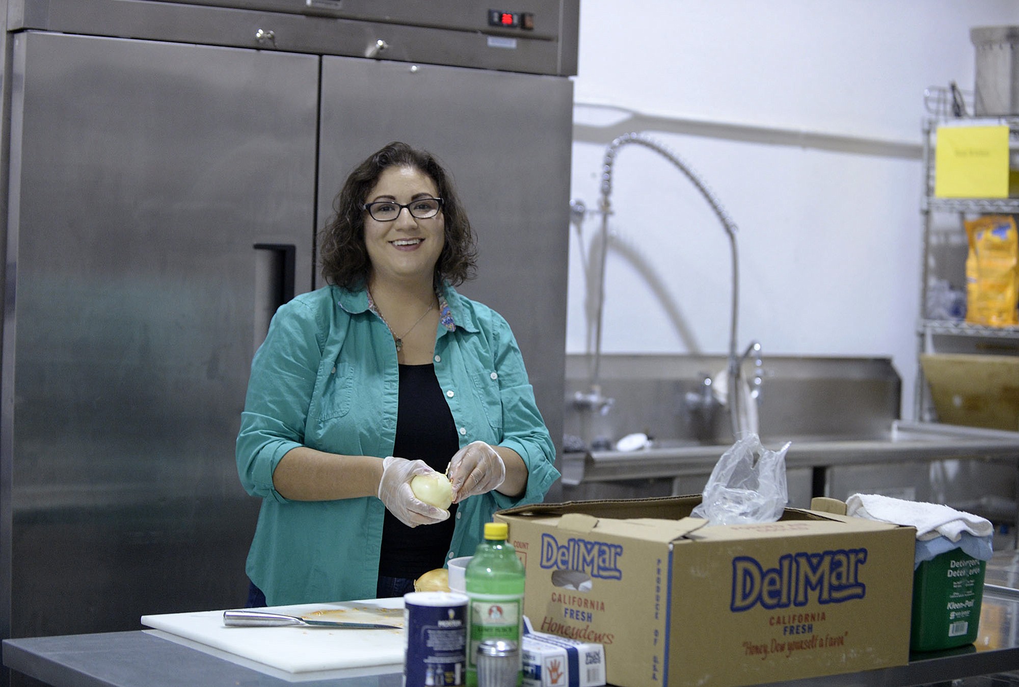 Carmen McKibben peels onions while making pico de gallo at Hour Kitchen on Thursday.