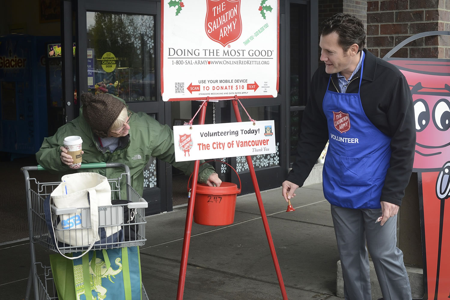 Volunteer bell ringer Tim Leavitt -- who moonlights as Vancouver mayor when he's not wearing that apron -- looks happy but chilly while thanking Dorothy Parkin for her donation during the first day of the Salvation Army's Red Kettle campaign.