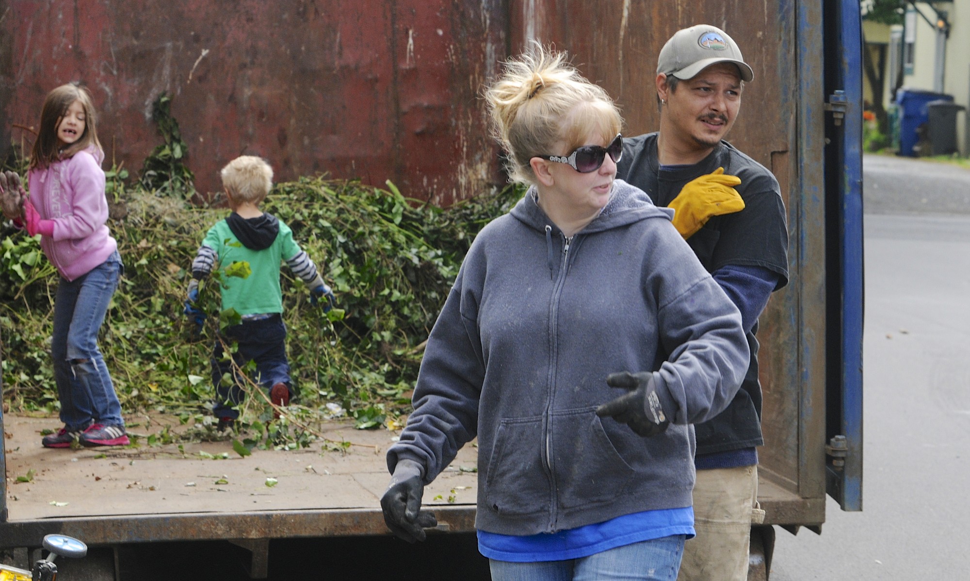 JP Simmons, right and Melissa Simmons, with James and Elizabeth Simmons at back, chat with a neighbor as they work on a yard cleanup at her father's house in Vancouver, Wa., Saturday June 14, 2014.