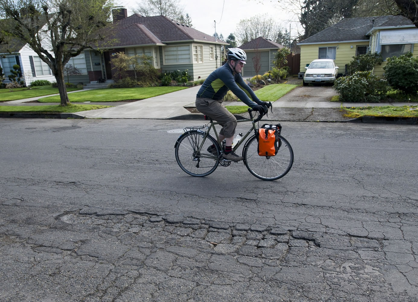 A cyclist pedals past a damaged section of Columbia Street in Vancouver in late March. The Commission on Street Funding was asked to issue a recommendation by mid-summer in case the City Council wanted to put a funding measure on November's ballot as part of the overall approach to road repairs.