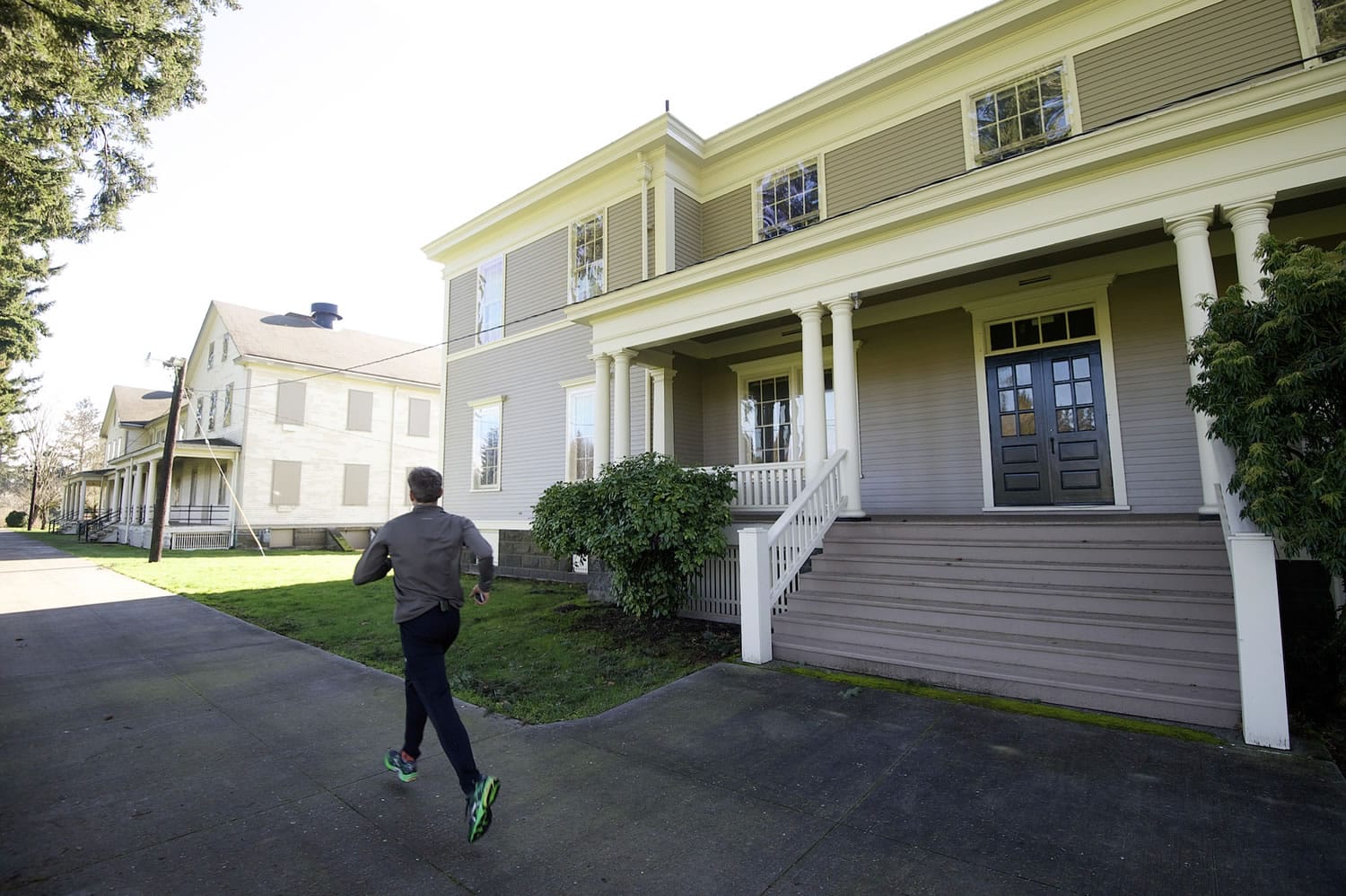 Photos by Steven Lane/The Columbian
The National Park Service has announced plans to renovate three &quot;front row&quot; barracks buildings at Fort Vancouver National Historic Site. A jogger Thursday goes past a smaller building, rehabbed in 2013, that shows what the other structures will look like.