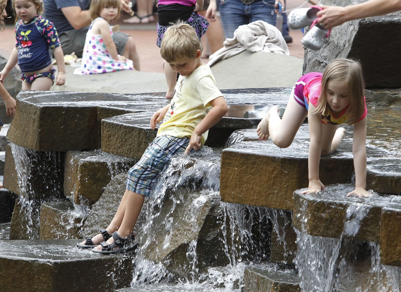 Children take advantage of a warm, muggy Saturday afternoon to enjoy the water feature at Vancouver's Esther Short Park.