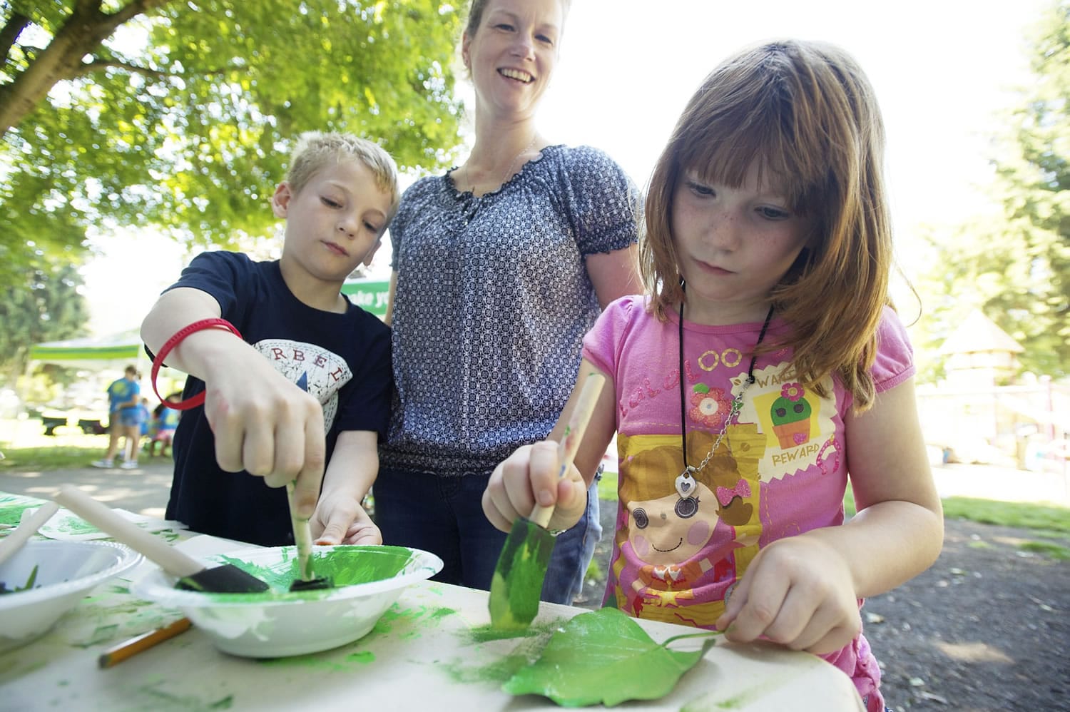 Photos by Steven Lane/The Columbian
Kevin Sheehan, 8, left, and sister Caoimhe Sheehan, 7, make leaf prints Wednesday at the Water Resources Education Center tent during the first Noon Concert at Esther Short Park in Vancouver.