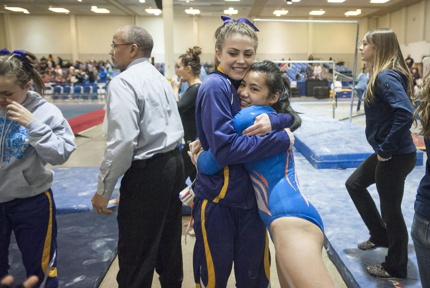 Sarah Ellis, left, of Columbia River High School congratulates Kylee Tjensvold of Ridgefield after her performance of the uneven bars at the 3A/2A gymnastic state championships in Tacoma on Saturday, Feb.