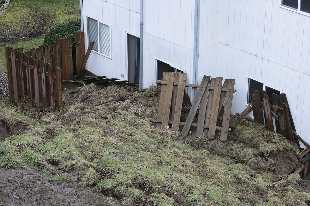 Sunday's landslide in Camas pushed a section of John Trost's backyard fence against his house.
