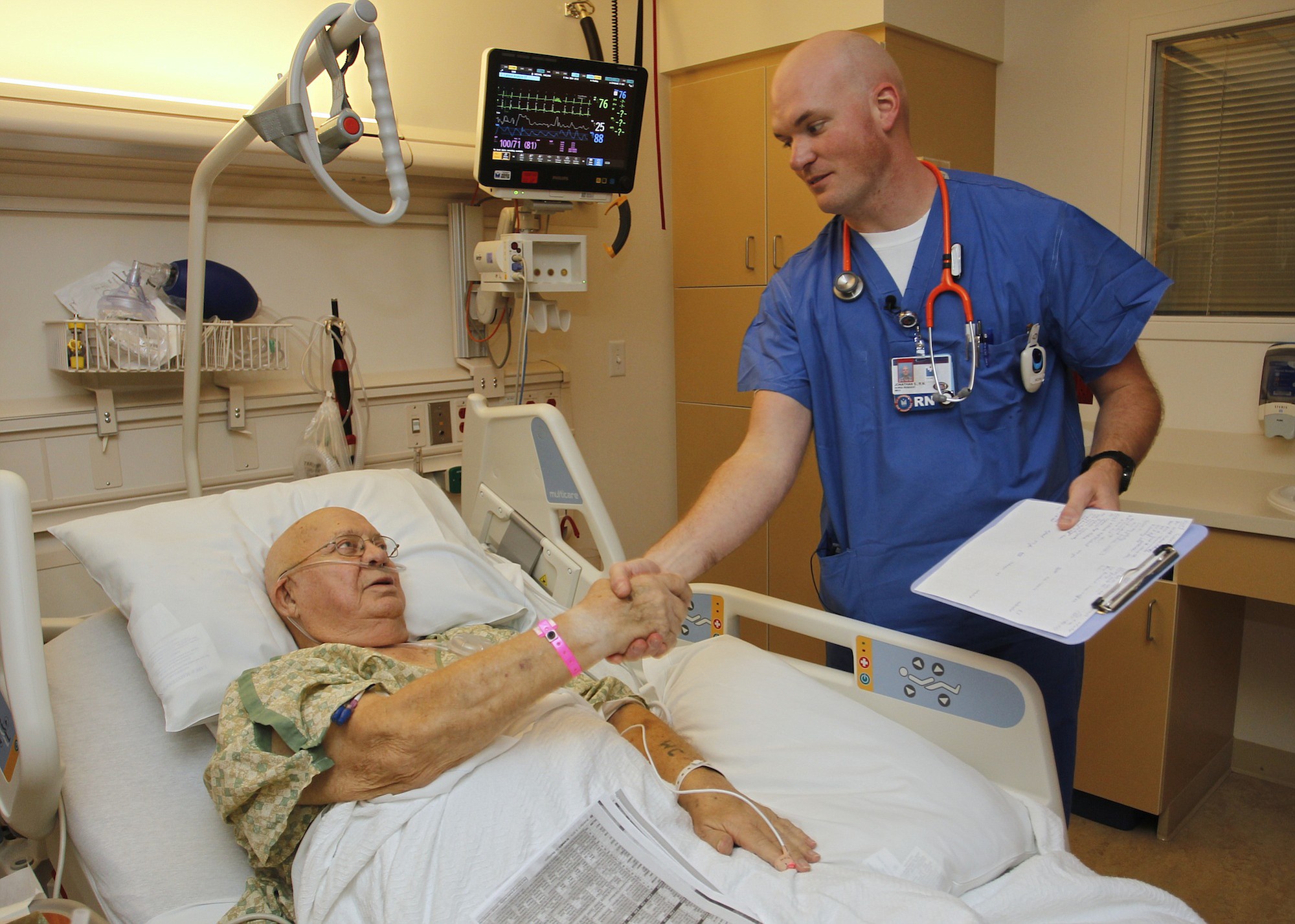 Registered nurse Jon Shinn visits with patient William C. Michael at Legacy Salmon Creek Medical Center. Shinn served in the U.S. Army Band Pershing's Own for six years, playing for more than 1,000 soldiers' funerals, before deciding to become a nurse.