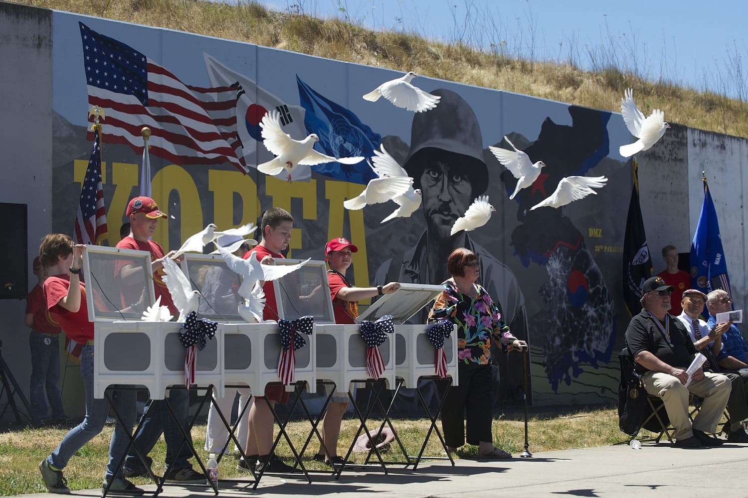 Patricia Quatier, center, watches as 51 white doves are released during Thursday's dedication of the Korean War mural on the downtown Remembrance Wall just south of City Hall.