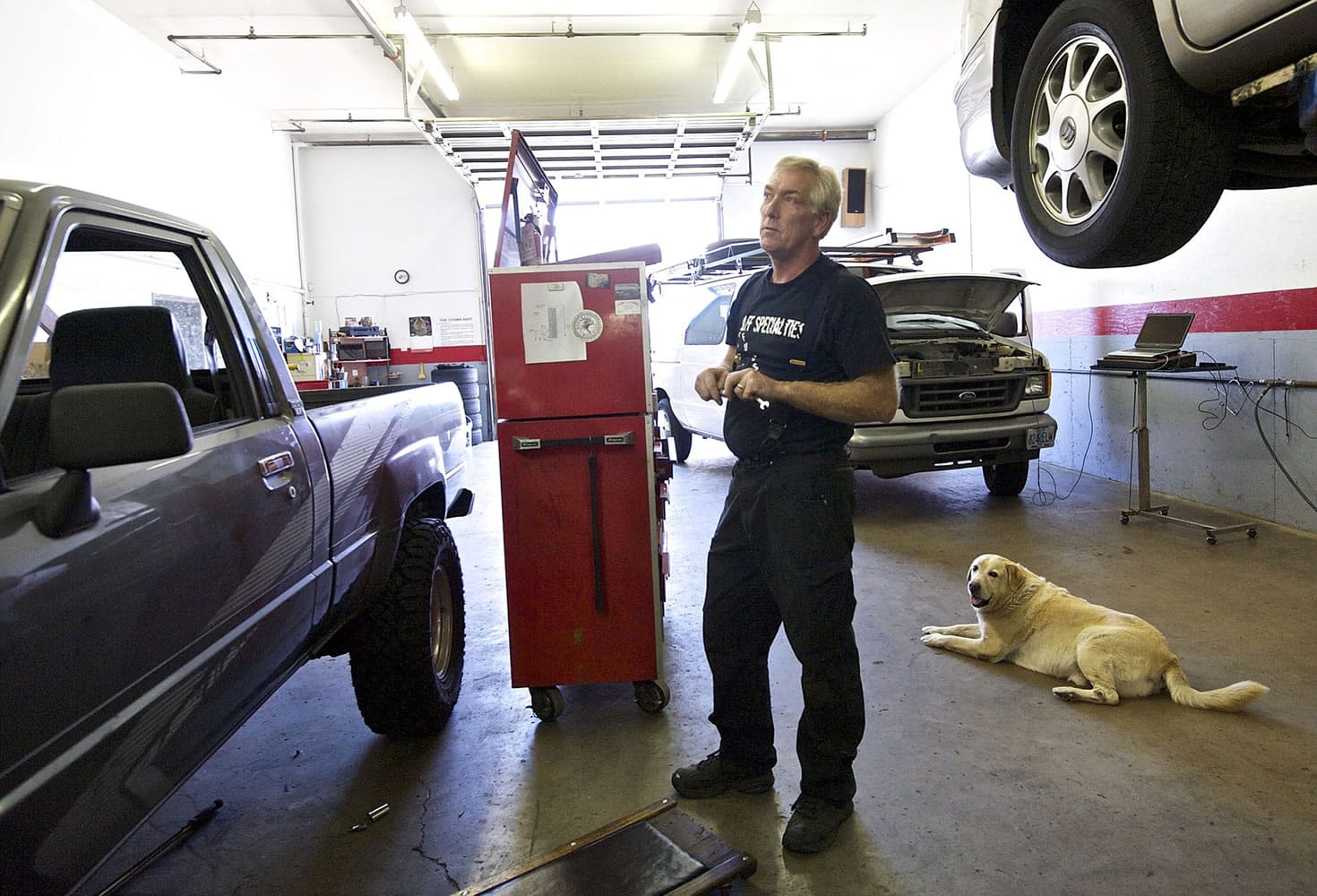 Dan Wolff works inside his shop with his dog Cody.