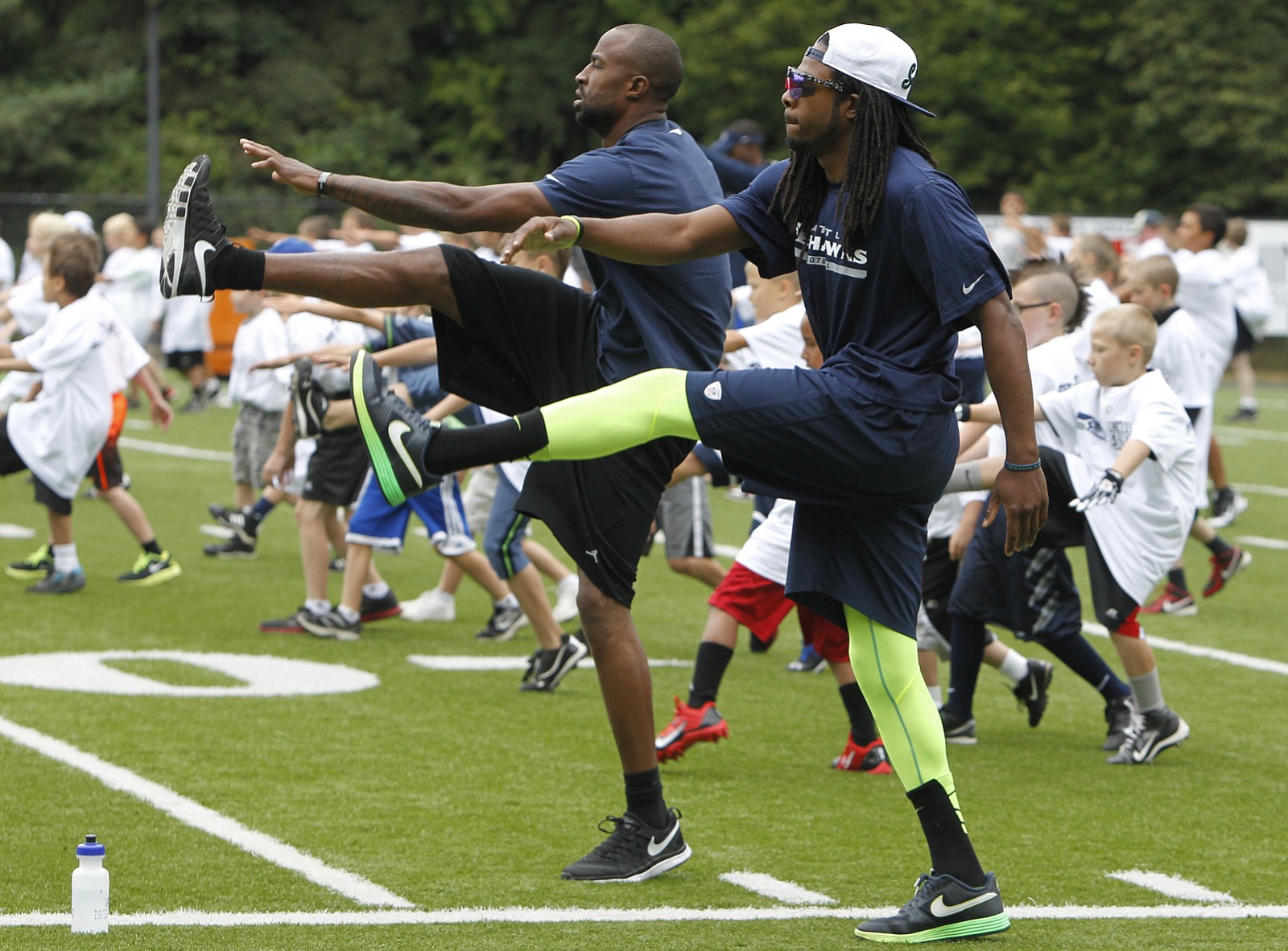 Seattle Seahawks cornerbacks Richard Sherman, right, and Brandon Browner get the kids stretched out prior to running drills at Kiggins Bowl.