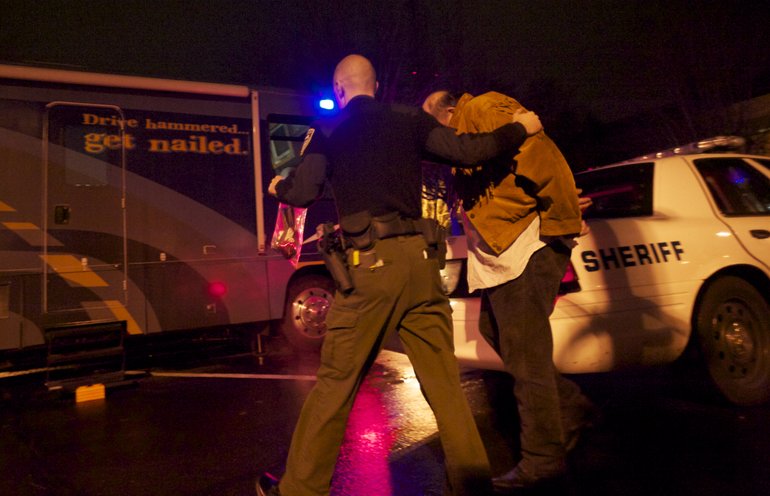 A Clark County Sheriff's deputy leads a suspected drunken driver into WSP's mobile Impaired Driving Unit.