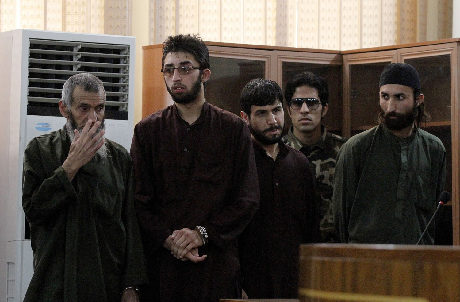 Four defendants are guarded by a security official, second from right, during their trial Wednesday in Kabul, Afghanistan.
