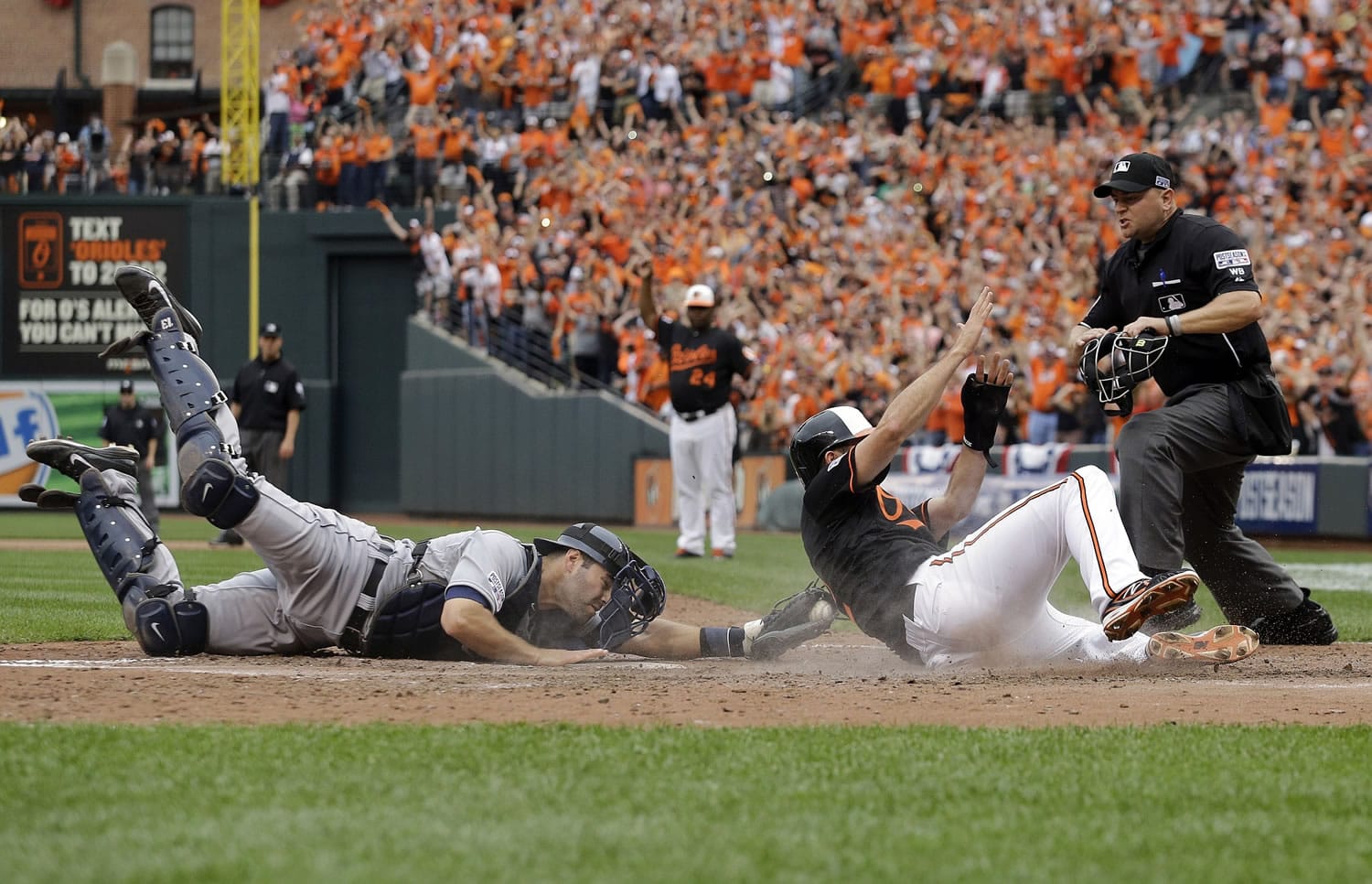 Detroit Tigers catcher Alex Avila, left, reaches but can't make the tag in time as Baltimore Orioles' J.J. Hardy scores on a double by Delmon Young in the eighth inning of Game 2 in the AL Division Series in Baltimore, Friday, Oct. 3, 2014. Baltimore won 7-6.