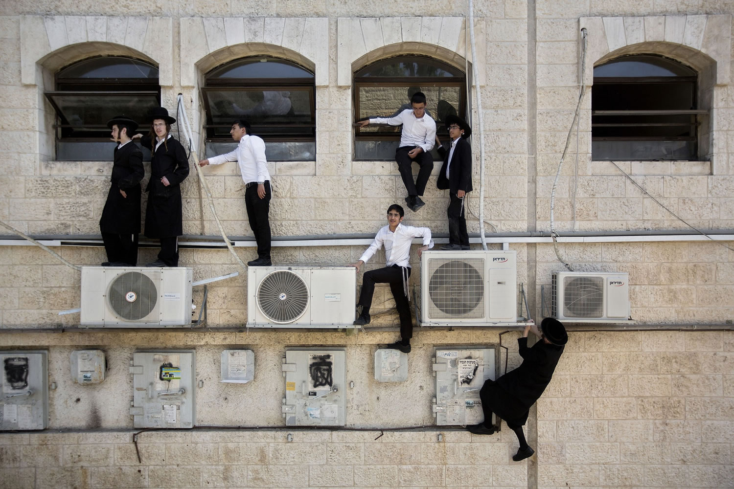 Ultra-Orthodox Jewish boys climb a wall to watch the scene of an attack in Jerusalem on Monday.