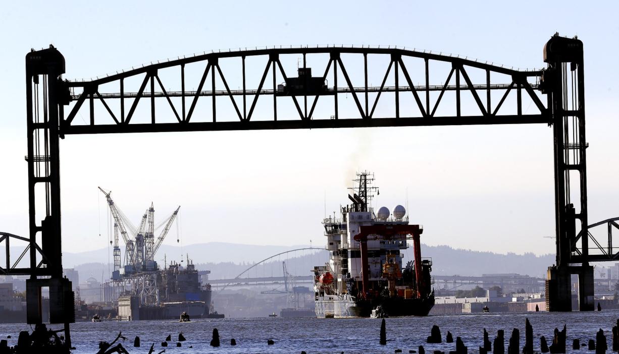 Royal Dutch Shell PLC icebreaker Fennica heads back to the Portland of Portland, at left, after it was blocked on its way to Alaska by activists hanging from the St. Johns bridge in Portland, Ore., Thursday, July 30, 2015. The icebreaker is a vital part of Shell's exploration and spill-response plan off Alaska's northwest coast. Environmental activists on St. Johns Bridge and kayakers on the Willamette River below have been blocking the icebreaker from heading to the Arctic for a drill operation.
