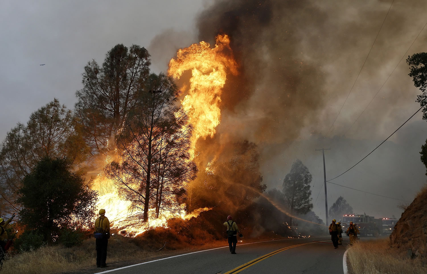 Firefighters spray a hose at a fire along Morgan Valley Road near Lower Lake, Calif., on Friday.