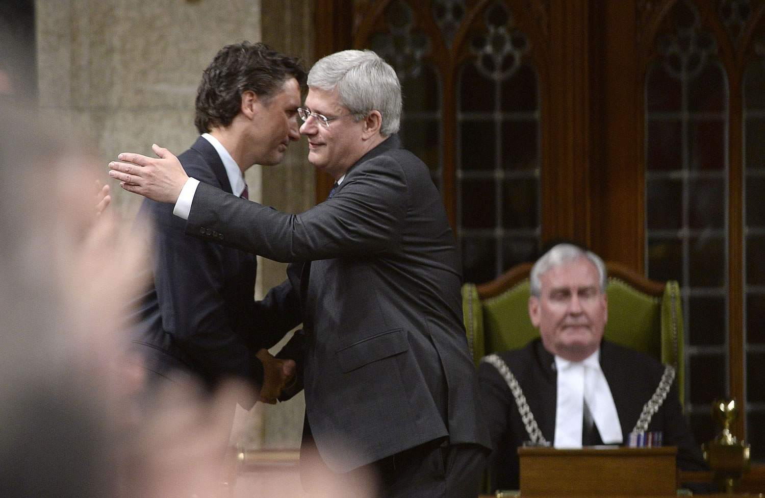Prime Minister Stephen Harper hugs the leader of the Liberal Party of Canada Justin Trudeau, as Sergeant-at-Arms Kevin Vickers, right, looks on in the House of Commons on Thursday in Ottawa.