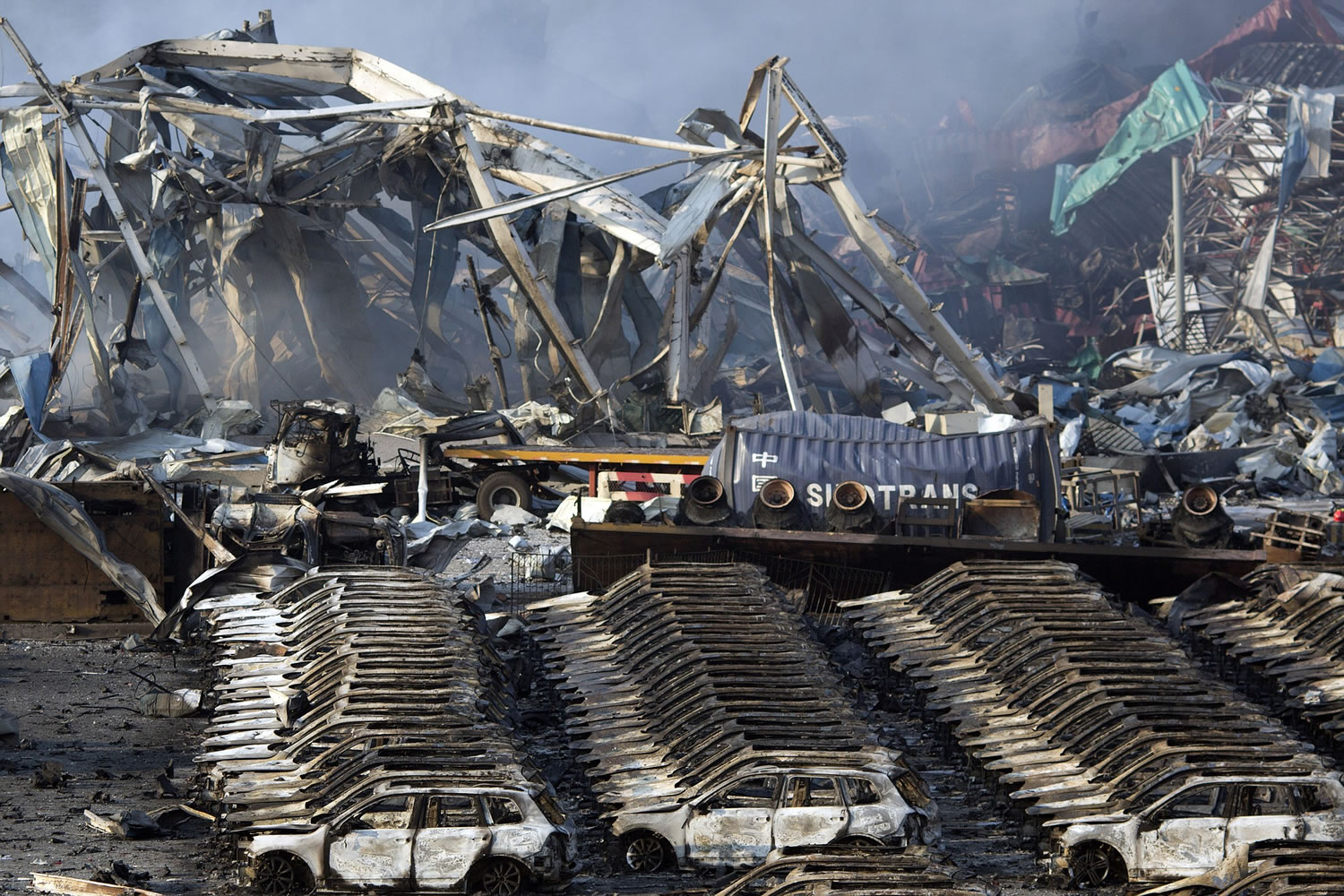 Charred remains of a warehouse and new cars are left burned after an explosion at a warehouse in northeastern China's Tianjin municipality, Thursday, Aug. 13, 2015. Huge, fiery blasts at a warehouse for hazardous chemicals killed many people and turned nearby buildings into skeletal shells in the Chinese port of Tianjin, raising questions Thursday about whether the materials had been properly stored.