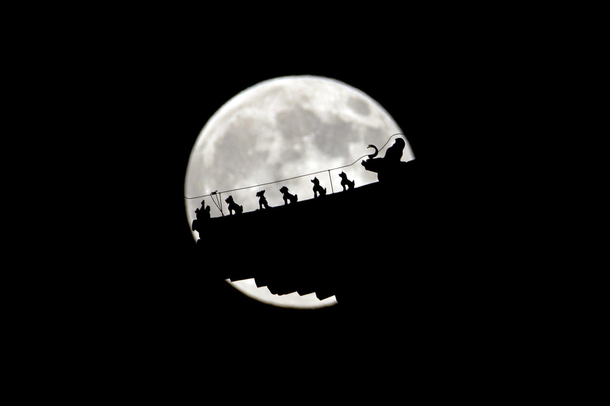 The July 12 perigee moon, also known as a supermoon, as it rises behind figurines on a Chinese pavilion in Beijing, China. The phenomenon, which scientists call a &quot;perigee moon,&quot; occurs when the moon is near the horizon and appears larger and brighter than other full moons.