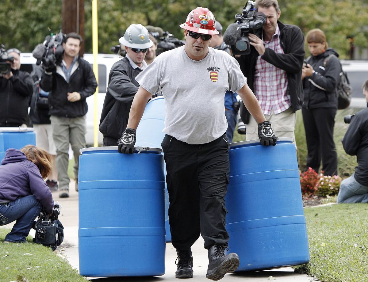 Protect Environmental workers move disposal barrels to a staging area outside the apartment of a healthcare worker who treated Ebola patient Thomas Eric Duncan and tested positive for the disease, Monday, Oct. 13, 2014, in Dallas.