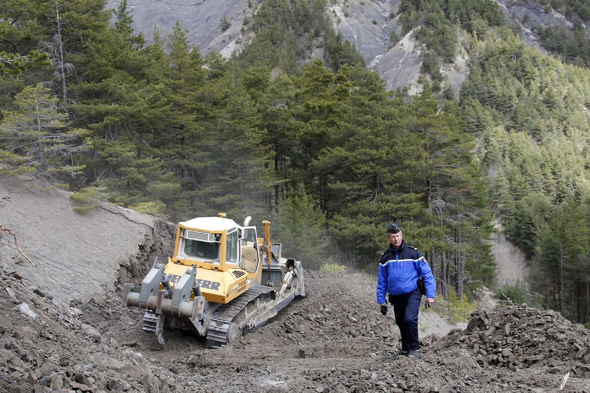 Gendarme Bruno Hermignies stands by a bulldozer clearing a path to the crash site near Seyne-les-Alpes, France, on Monday.