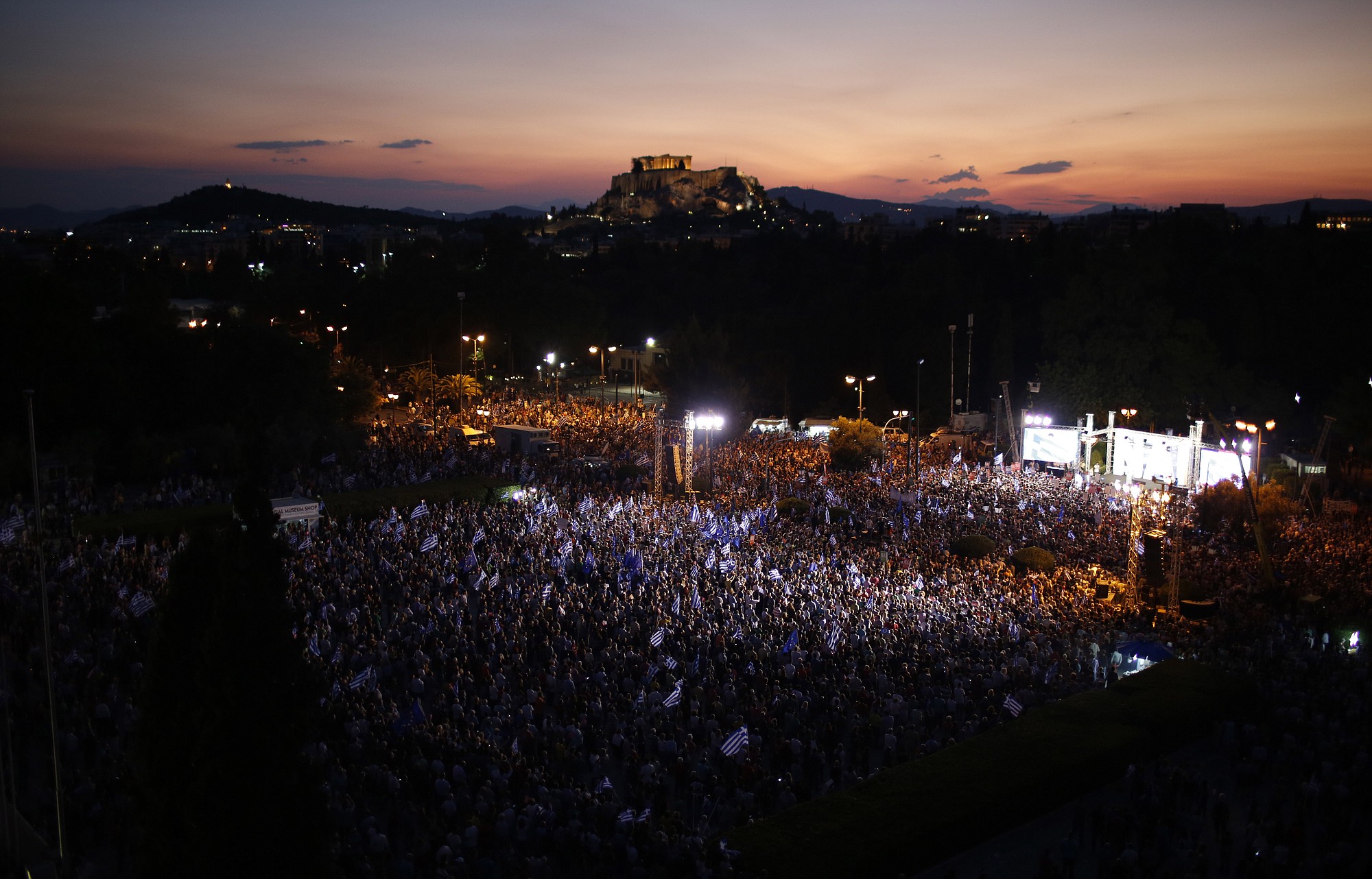 Demonstrators gather during a rally organized by supporters of the Yes vote as the ancient Acropolis hill is seen in the background in Athens, Friday, July 3, 2015. A new opinion poll shows a dead heat in Greece's referendum campaign with just two days to go before Sunday's vote on whether Greeks should accept more austerity in return for bailout loans.