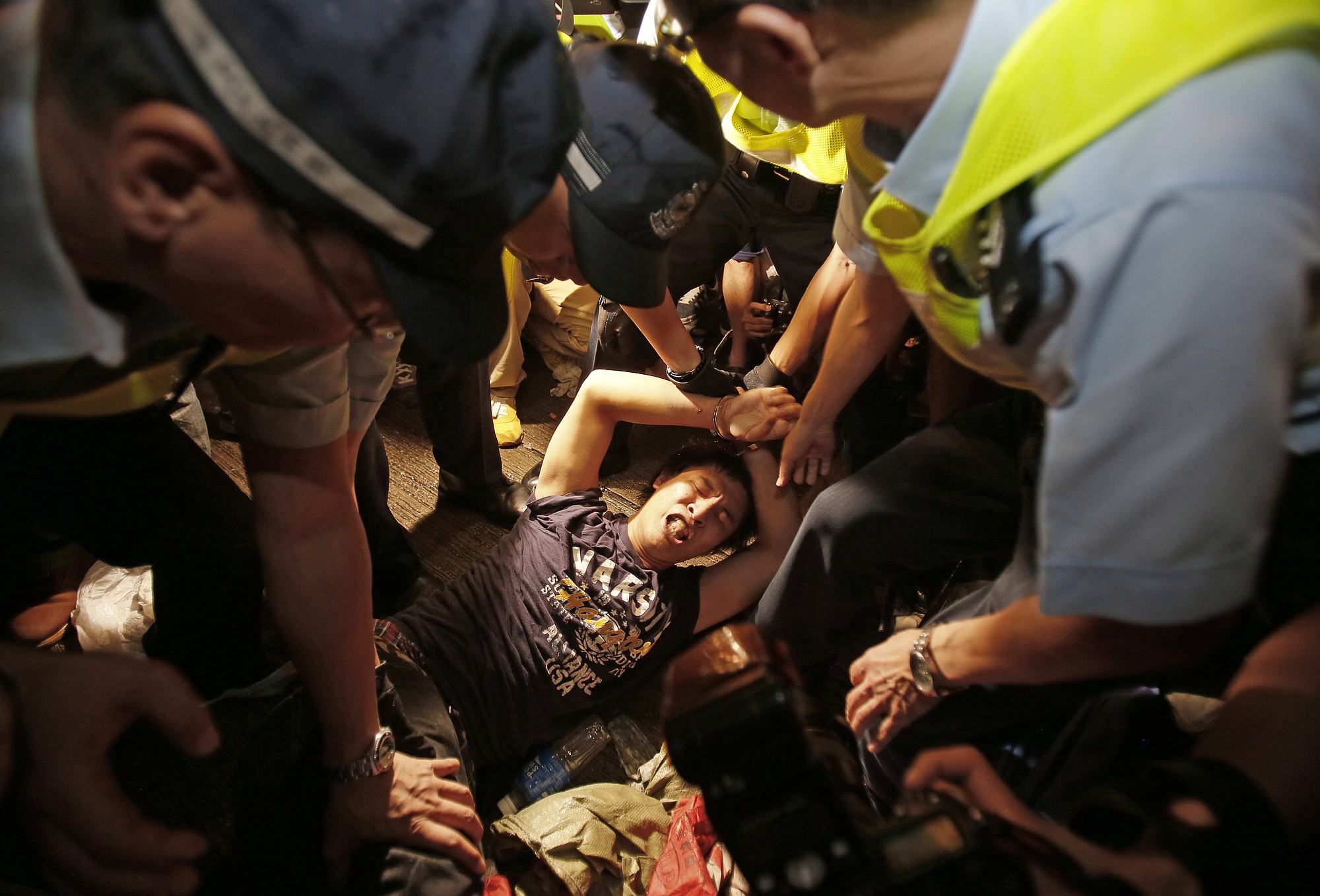 A man is cuffed by police and taken from the confrontation of pro-democracy student protesters and angry local residents Friday in Hong Kong.