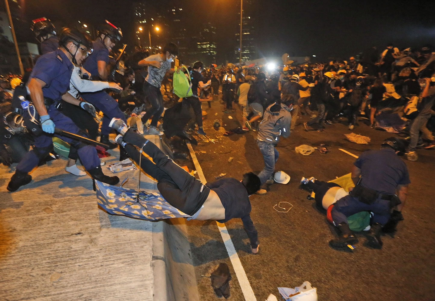 Police officers throw a pro-democracy protester on the main road outside government headquarters Sunday in Hong Kong.