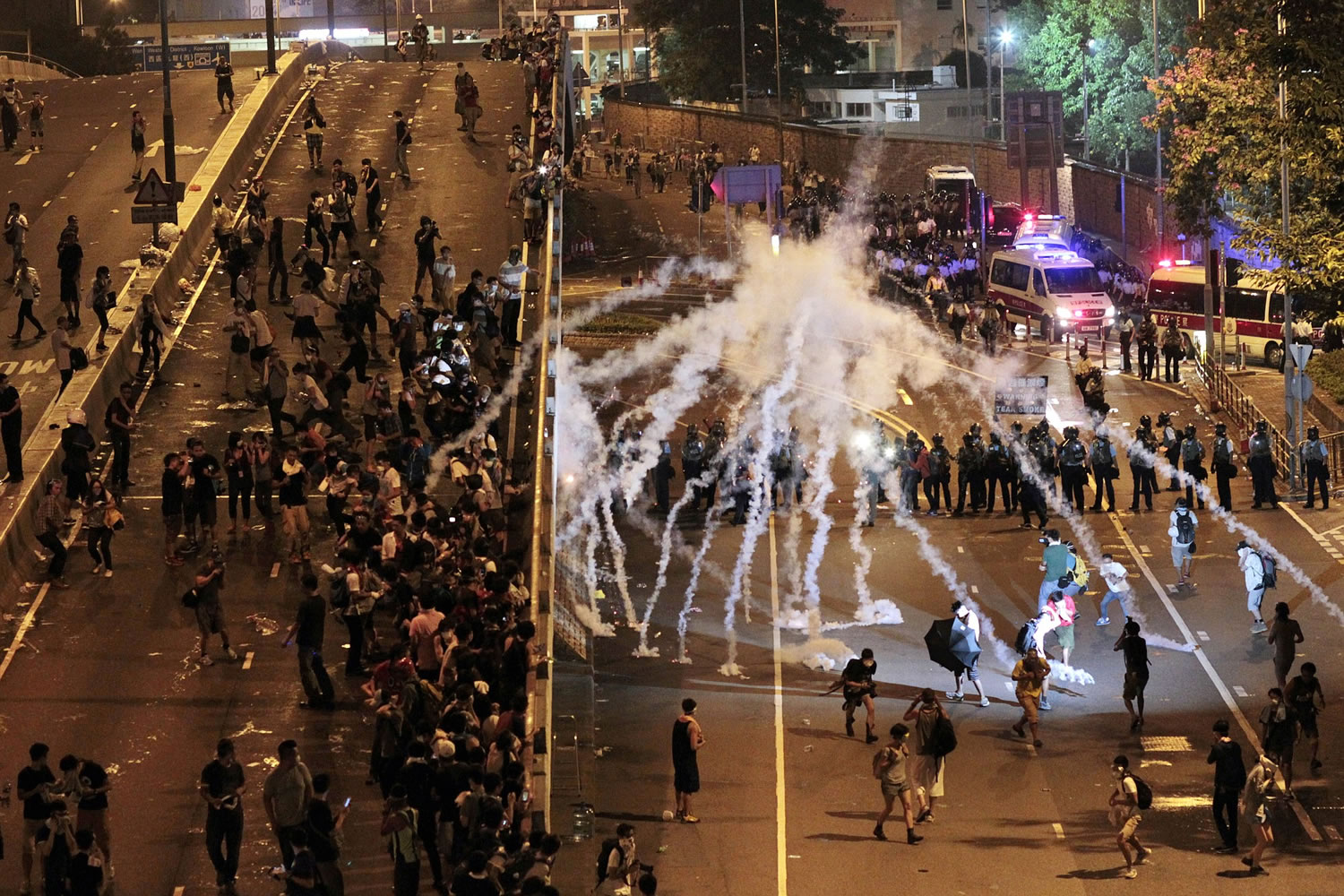 Riot police fire tear gas on student protesters occupying streets surrounding the government headquarters in Hong Kong, early Monday, Sept. 29, 2014. Pro-democracy demonstrators defied onslaughts of tear gas and appeals from Hong Kong's top leader to go home, as the protests over Beijing's decision to limit political reforms expanded across the city early Monday.