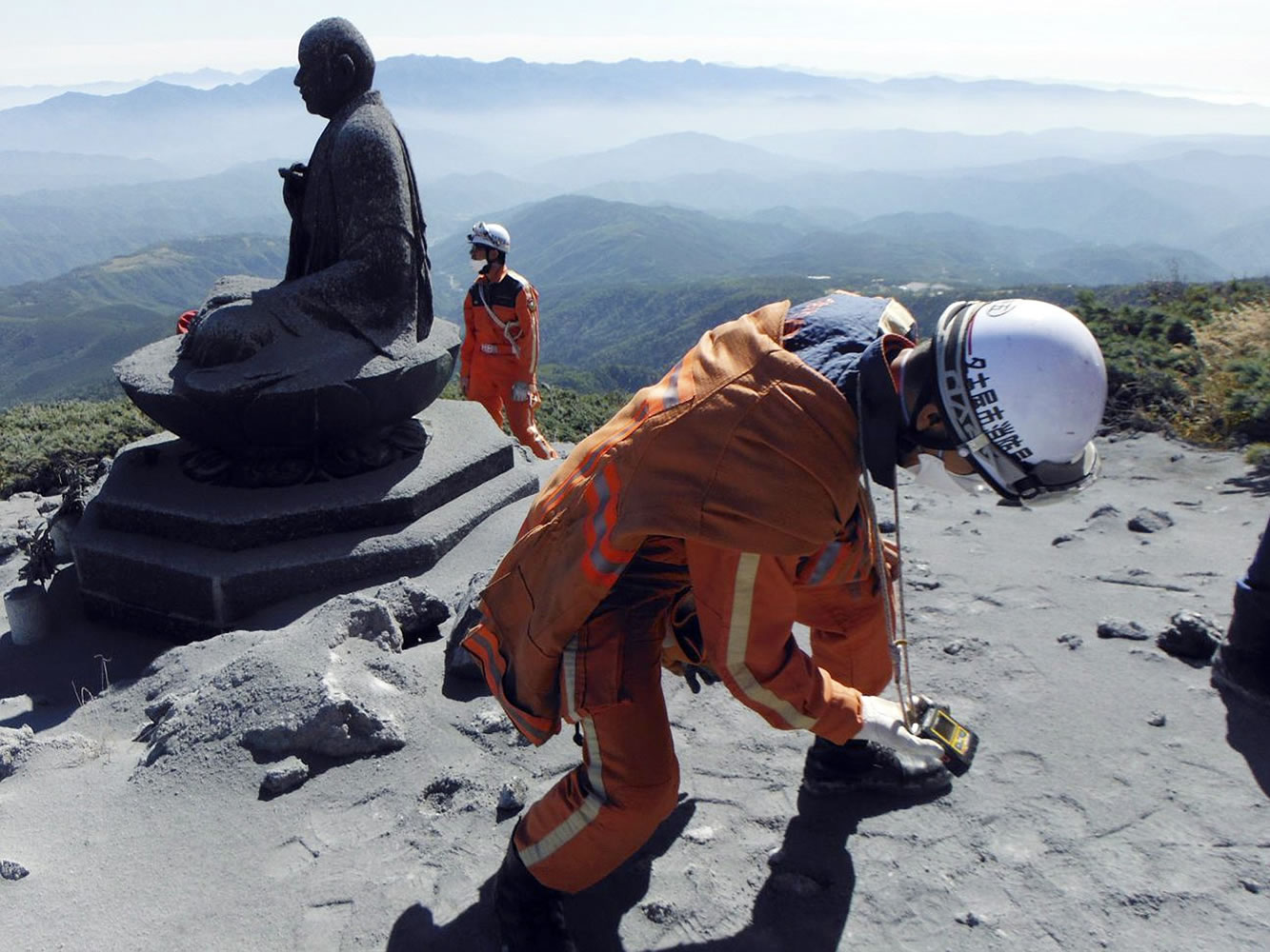 A Nagoya City firefighter uses a gas analyzer to check toxic volcanic fumes next to a Buddha statue near the summit of the Mount Ontake in central Japan.
