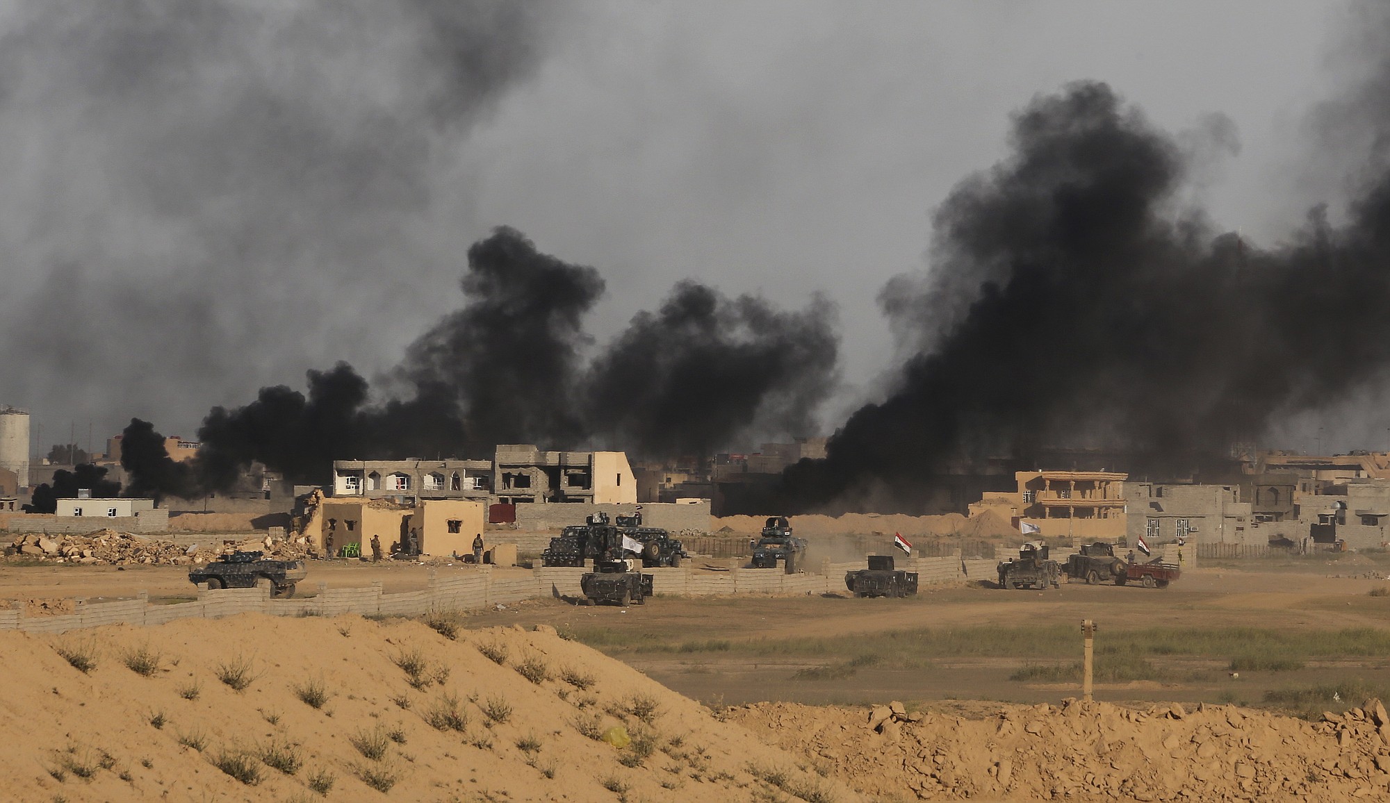 Iraqi security forces prepare to attack Islamic State extremist positions as smoke rises from central Tikrit during clashes in the city, 130 kilometers (80 miles) north of Baghdad, Iraq, on Friday.
