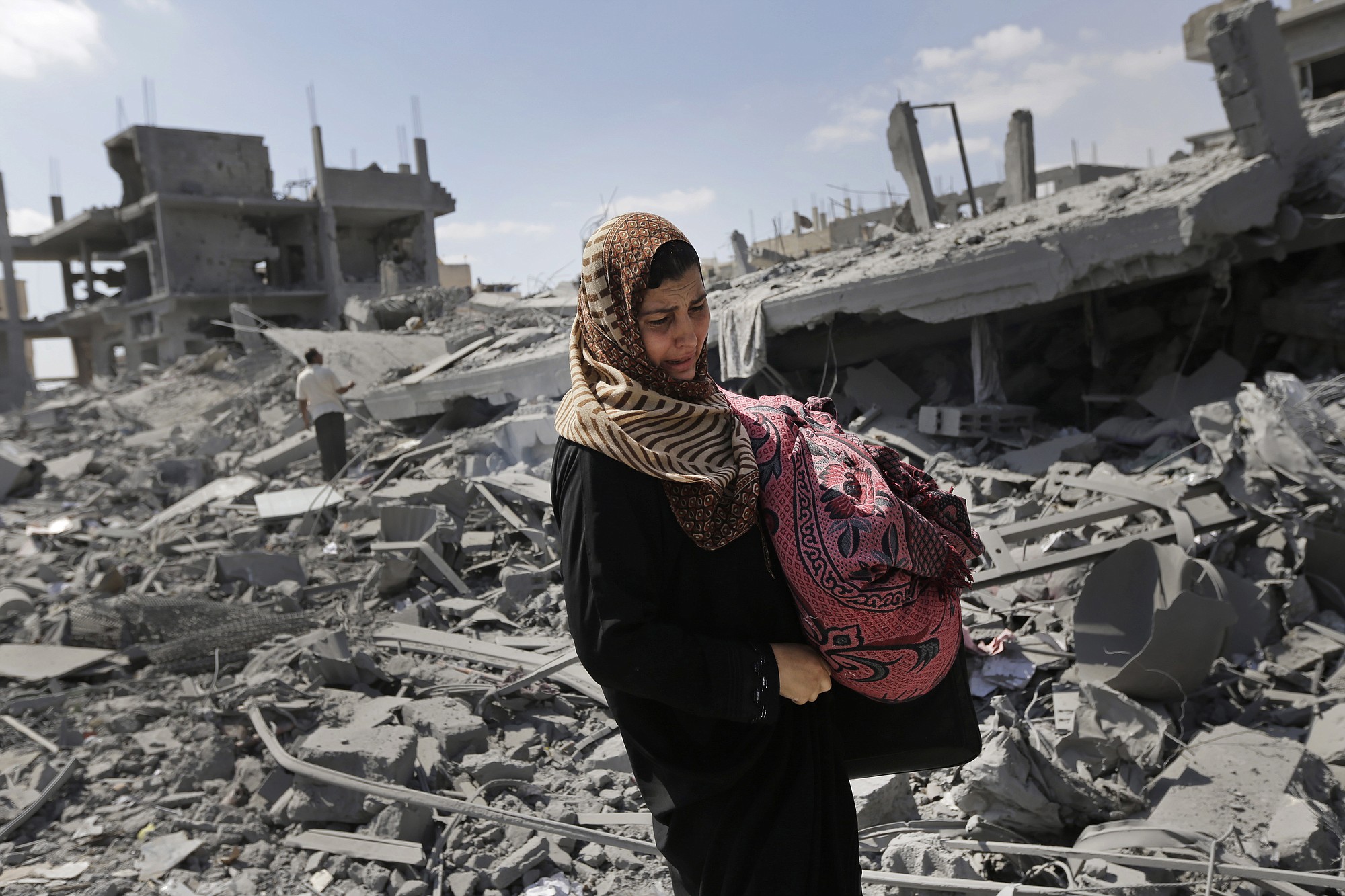 A Palestinian woman carries her belongings Saturday past the rubble of houses destroyed by Israeli strikes in Beit Hanoun, northern Gaza Strip.