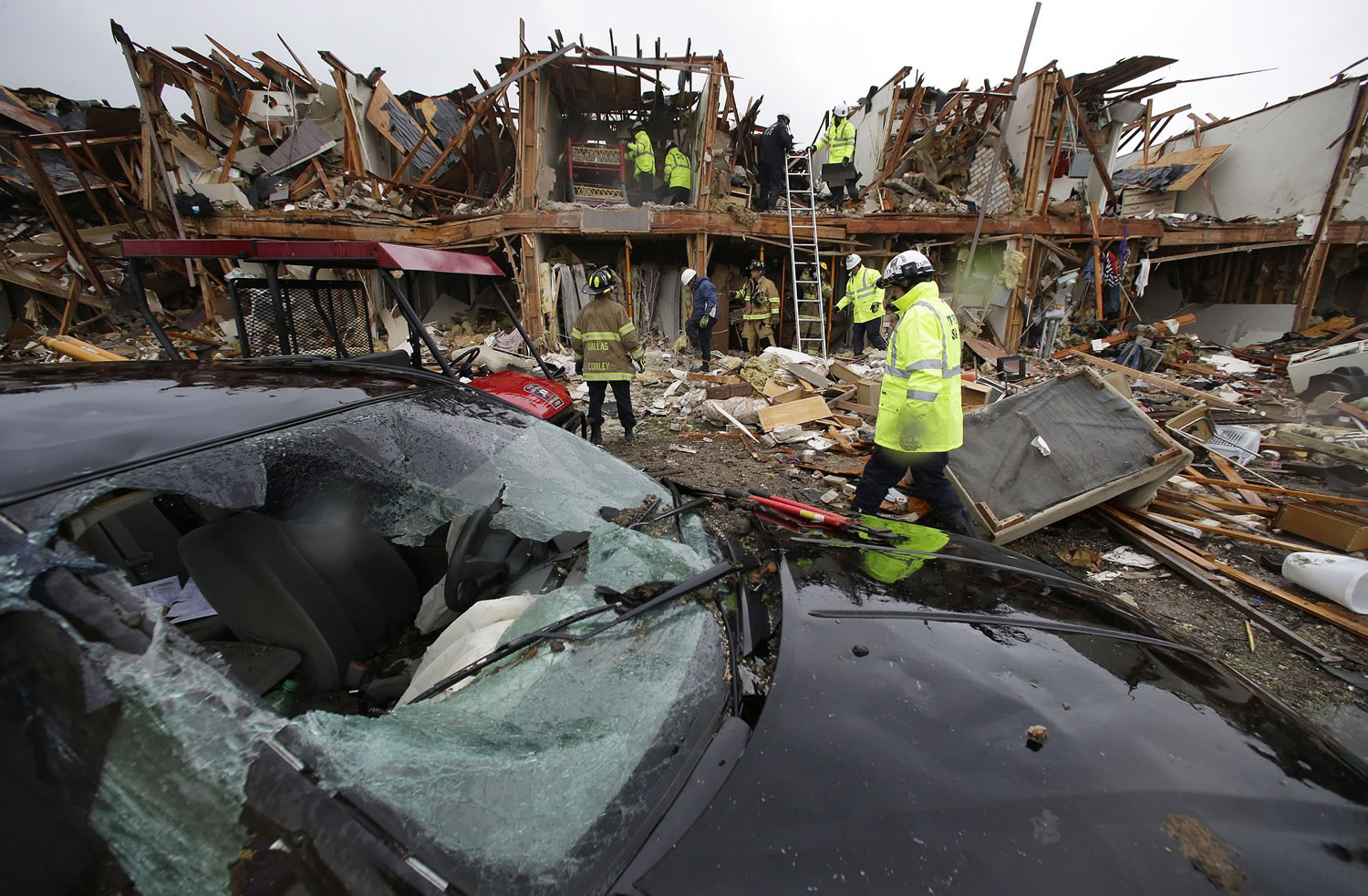 A smashed car sits in front of an apartment complex destroyed by an explosion at a fertilizer plant in West, Texas, as firefighters conduct a search and rescue Thursday. A massive explosion at the West Fertilizer Co.