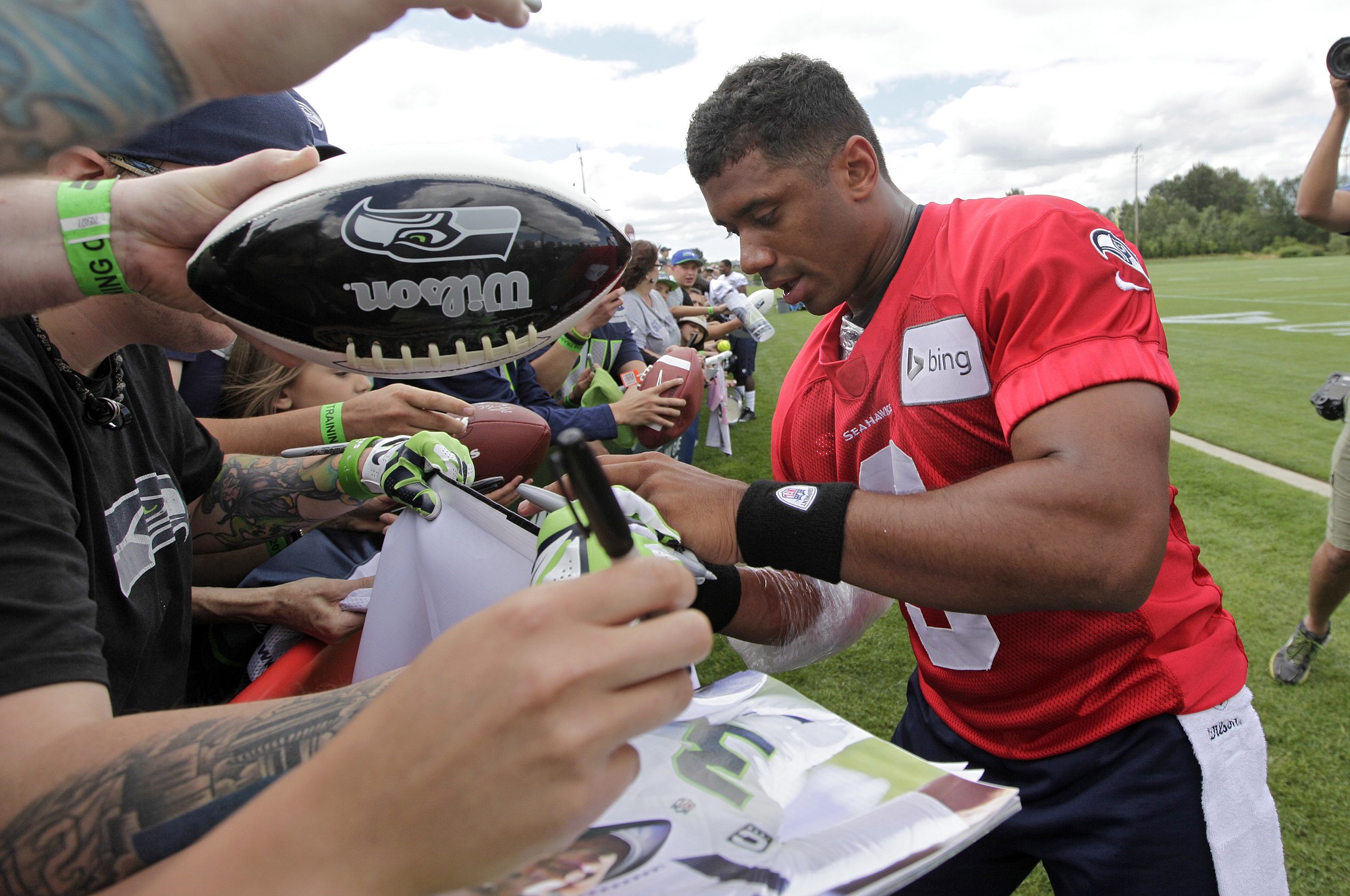 Seattle Seahawks quarterback Russell Wilson signs autographs following an NFL football camp practice Friday, July 25, 2014, in Renton, Wash.