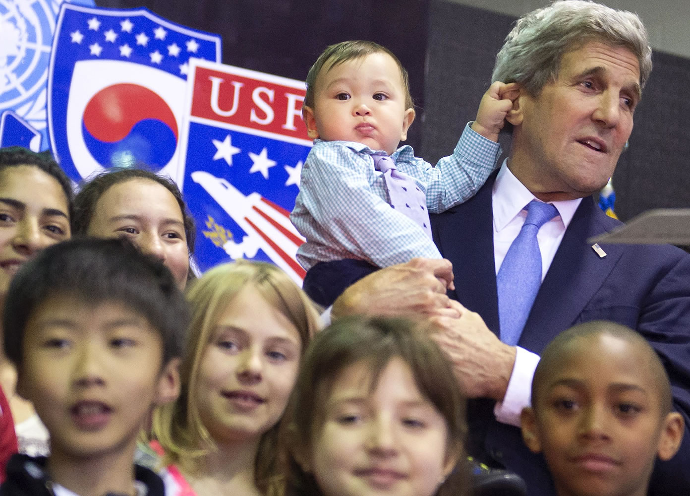 U.S. Secretary of State John Kerry, right, holds 8-month-old Andrew Belz as he poses Monday for photos with the children of U.S. troops and U.S.