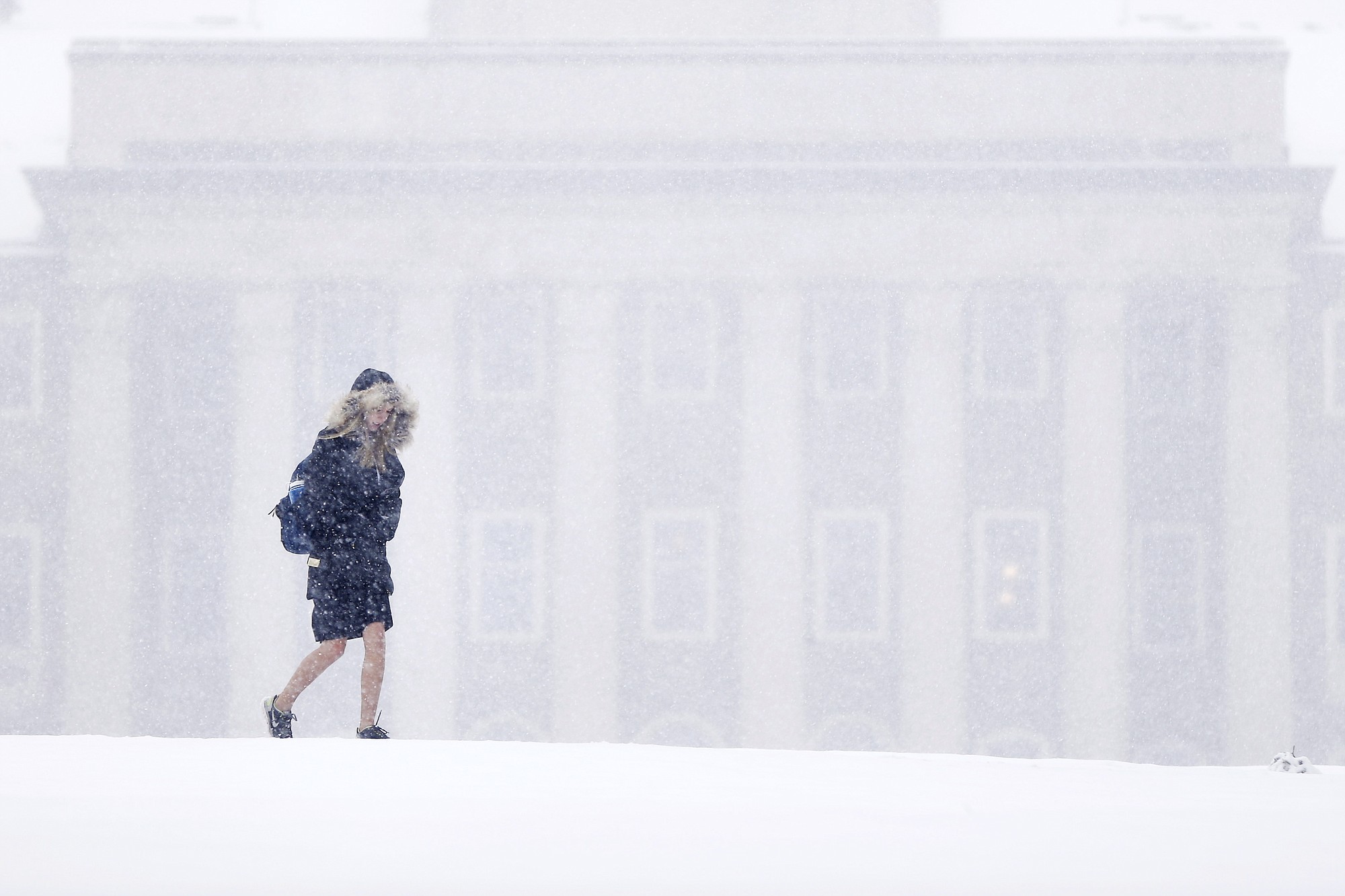 A young woman walks in view of Old Main on the Penn State University campus during a snowstorm Friday in State College, Pa.  Forecasters say a storm will dump up to 6 inches of snow on the Northeast and mid-Atlantic on Friday. New England will be on the lower end of the snow totals but even Boston, which has seen a record 108.6 inches of snow, could get an inch or more.