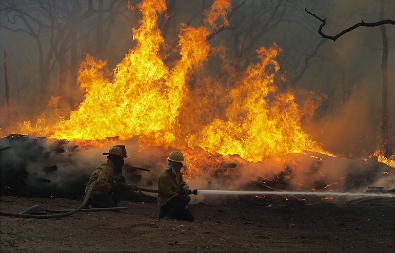 Firefighters from around the state battle a large wildfire on Highway 71 near Smithville, Texas, Monday.