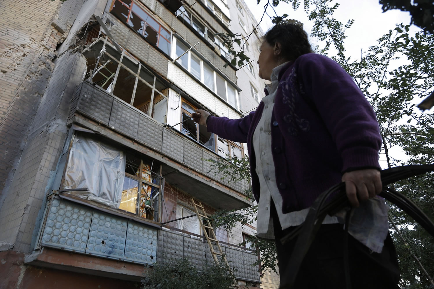 A woman points Sunday to a damaged building after shelling in the city of Slovyansk, Donetsk Region, eastern Ukraine.