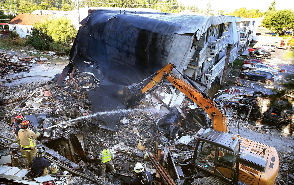 Firefighters hose down the debris field from the collapsed east side of the Bremerton Motel 6, Wednesday morning, Aug. 19, 2015. A gas explosion leveled the building Tuesday evening. The blast critically injured a gas company worker minutes after the acting hotel manager had evacuated the building due to a gas leak.