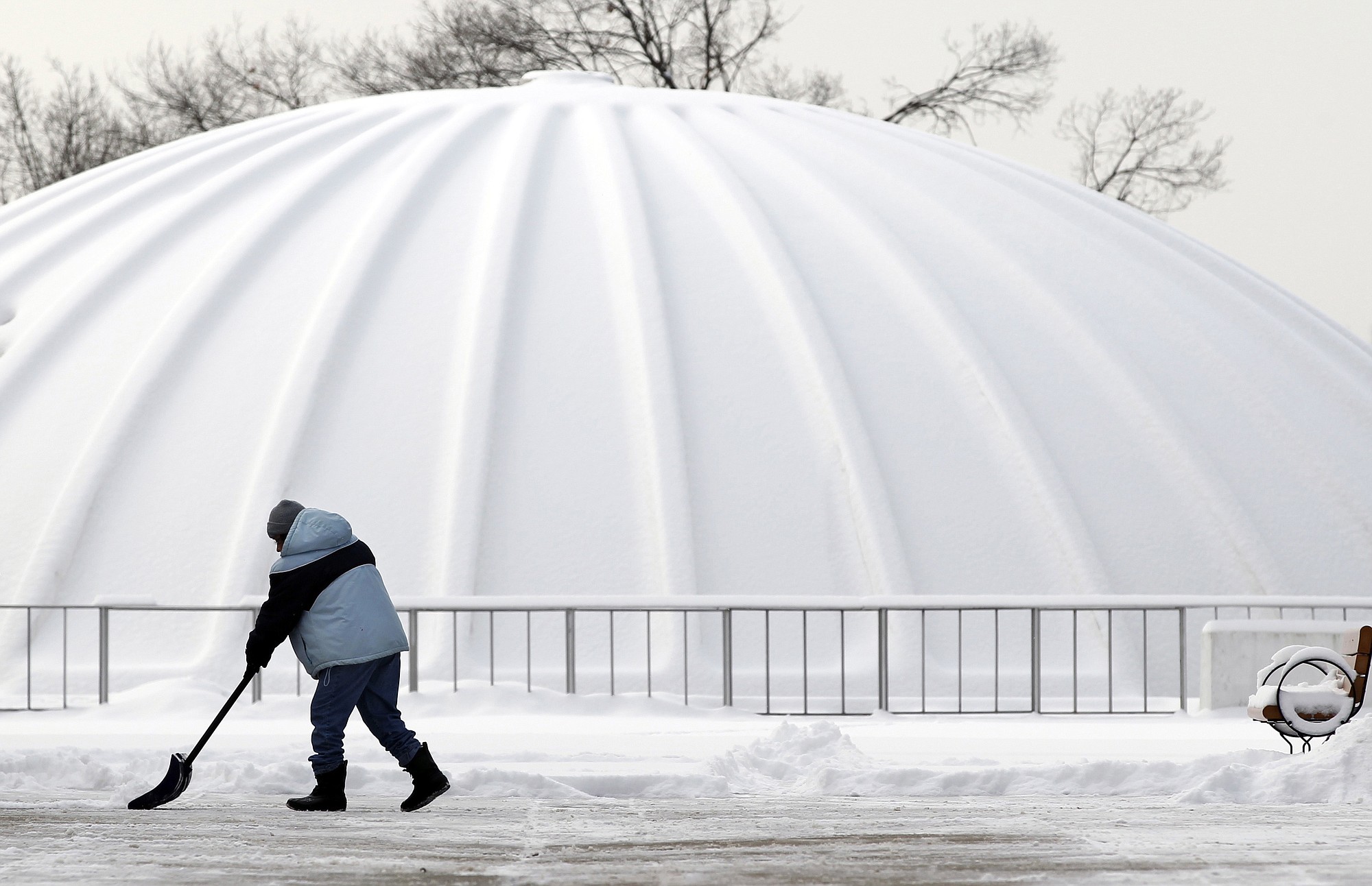 After an overnight storm dropped fresh snow, a worker shovels near the planetarium at the New Jersey State Museum on Tuesday in Trenton, N.J.